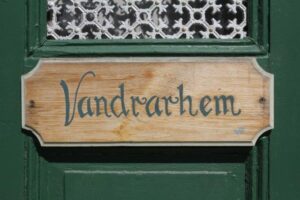 Hand-painted wooden sign saying Vandrarhem (hostel) on a green door