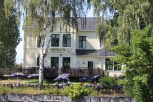 Strömsborg between the birch trees, with guests at the outdoor seating