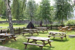 Picnic tables on the lawn by the outdoor seating, with the river in the background