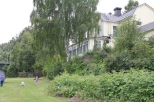 The lawn below Strömsborg where children are playing, with the house behind the trees
