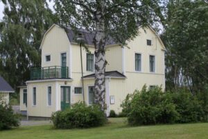 The yellow hostel house with green details, surrounded by greenery